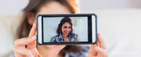 Woman taking a selfie on a smartphone. Used to illustrate the article: Why you should think twice about your profile picture, by SmartFrame Technologies