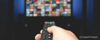Hand holding a remote control pointing at a TV