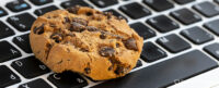 Close up of chocolate chip cookie on the keyboard of a laptop. Image used to illustrate the SmartFrame blog: 'Will the cookie ever die? Google delays phase out on Chrome until 2024'