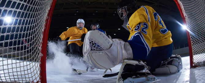 ice hockey goalkeeper saving shot from player