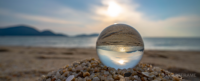 Transparent ball on rocks at a beach with a sunset behind.